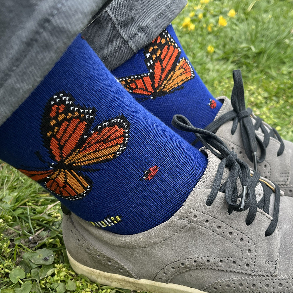 Made in USA men's blue cotton socks featuring a variety of friendly bugs: monarch butterflies, a caterpillar, honeybees, ladybugs, and a dragonfly (by THIS NIGHT)