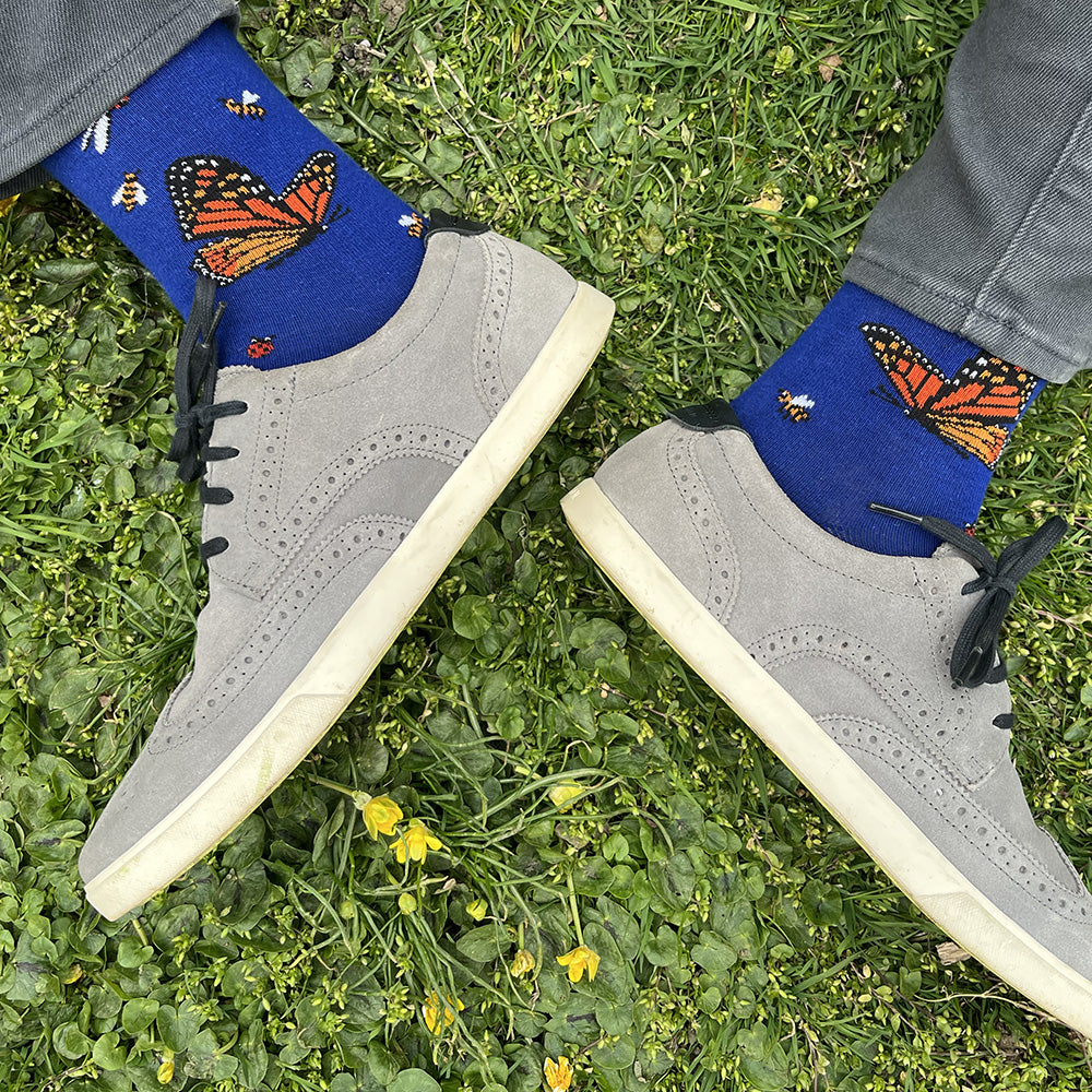 Made in USA men's blue cotton socks featuring a variety of friendly bugs: monarch butterflies, a caterpillar, honeybees, ladybugs, and a dragonfly (by THIS NIGHT)
